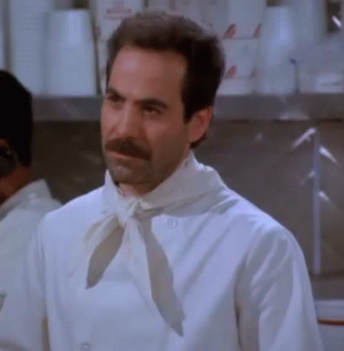 A Man With A Beard And Mustache Wearing A White Chef 'S Coat And Tie . GIF