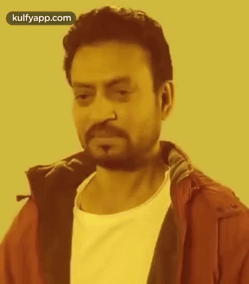 A Man With A Beard And Nose Ring Is Wearing A Red Jacket And White Shirt . GIF