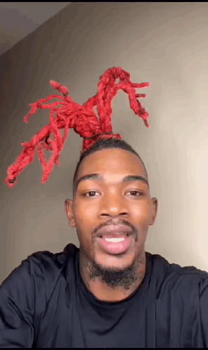 A Man With A Beard And Red Dreadlocks On His Head Is Smiling For The Camera . GIF