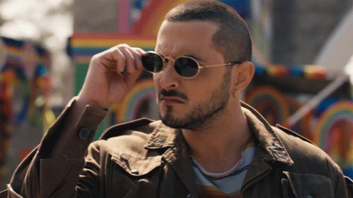 A Man With A Beard And Sunglasses Adjusts His Glasses GIF