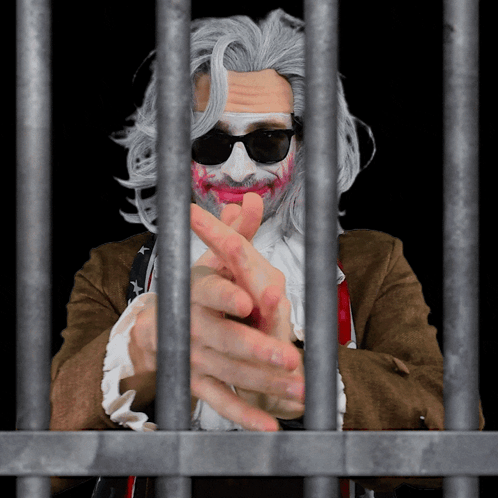 A Man With A Beard And Sunglasses Is Behind Bars With His Hands Crossed GIF