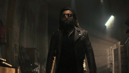 A Man With A Beard And Sunglasses Is Standing In A Hallway GIF