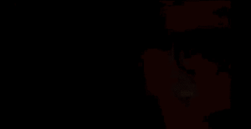 A Man With A Beard And Sunglasses Is Standing In Front Of A Red Sign . GIF