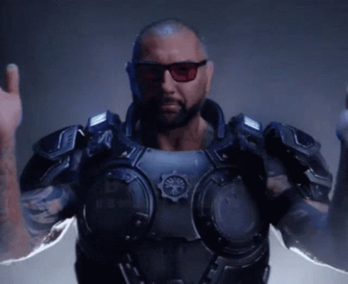 A Man With A Beard And Sunglasses Is Wearing A Futuristic Armored Suit . GIF