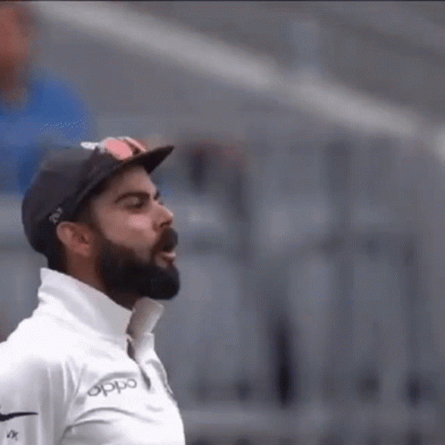 A Man With A Beard And Sunglasses Is Wearing A Hat And A White Shirt . GIF