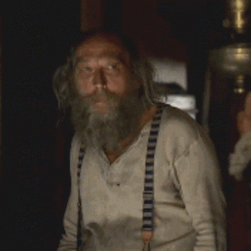 a man with a beard and suspenders is looking at something