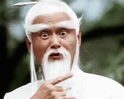 A Man With A Beard And White Hair Is Pointing At The Camera . GIF