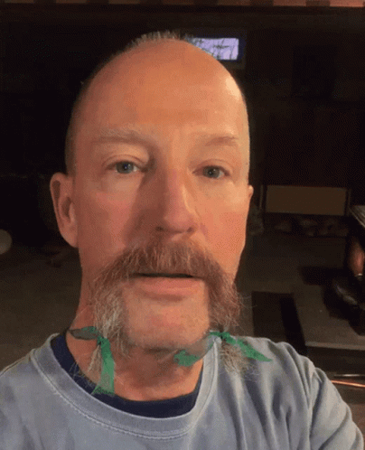 A Man With A Beard Has A Green Ribbon Tied Around His Neck GIF