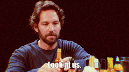 A Man With A Beard Holds A Bottle Of Hot Sauce And Says " Look At Us " GIF