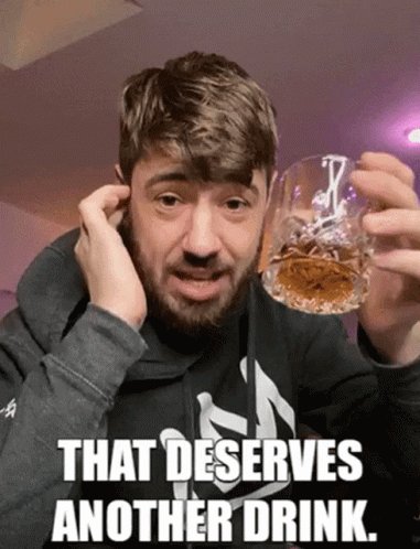 A Man With A Beard Holds A Glass Of Whiskey With The Caption That Deserves Another Drink GIF