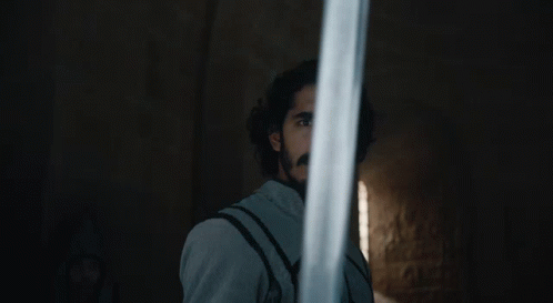 A Man With A Beard Holds A Sword In Front Of His Face GIF
