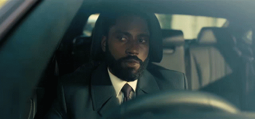 A Man With A Beard In A Suit And Tie Is Driving A Car GIF