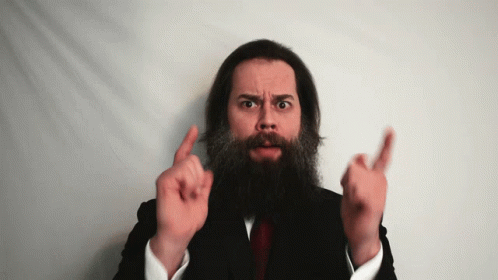 A Man With A Beard In A Suit And Tie Is Pointing Up GIF