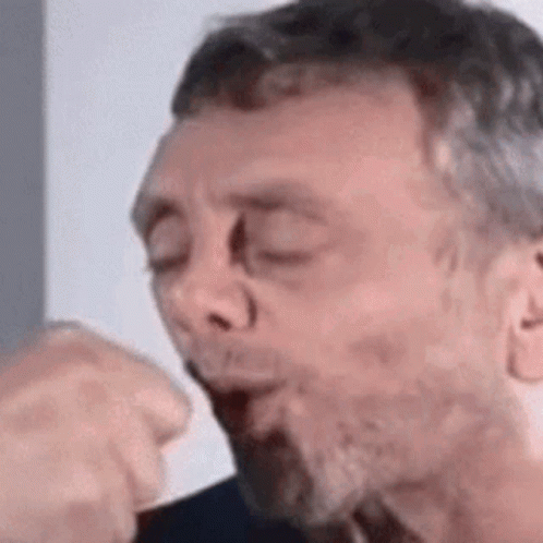 A Man With A Beard Is Blowing A Kiss . GIF