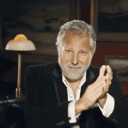 A Man With A Beard Is Clapping His Hands In A Dark Room GIF