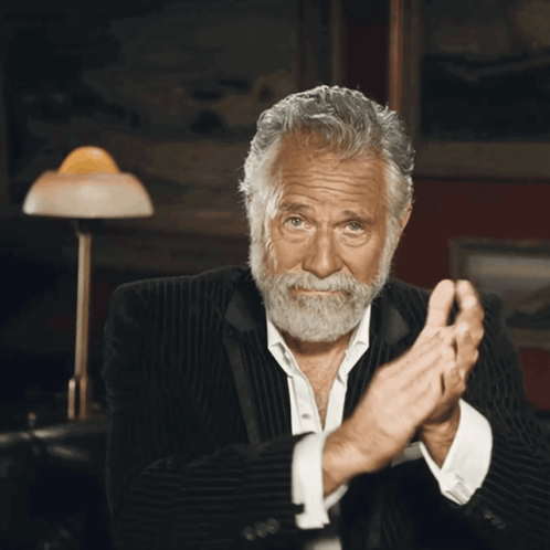 A Man With A Beard Is Clapping His Hands In A Dark Room GIF