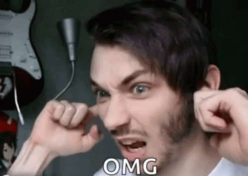 A Man With A Beard Is Covering His Ears With His Hands And Making A Face . GIF