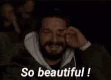 A Man With A Beard Is Covering His Eyes While Watching A Movie And The Words `` So Beautiful '' Are Above Him . GIF
