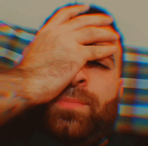 A Man With A Beard Is Covering His Face With His Hands GIF
