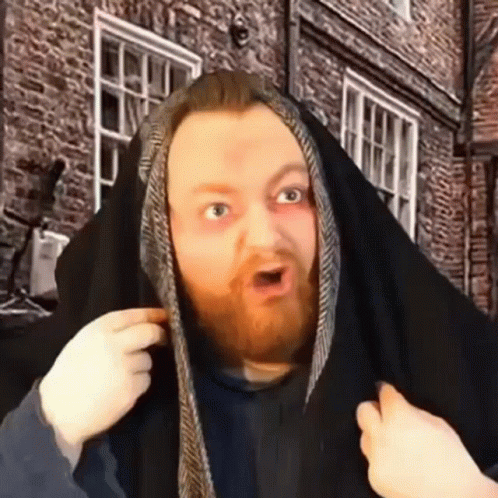 A Man With A Beard Is Covering His Head With A Black Cloth . GIF