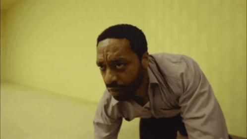 A Man With A Beard Is Crawling On The Floor With His Eyes Closed GIF