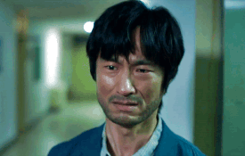 A Man With A Beard Is Crying In A Hallway With His Eyes Closed GIF