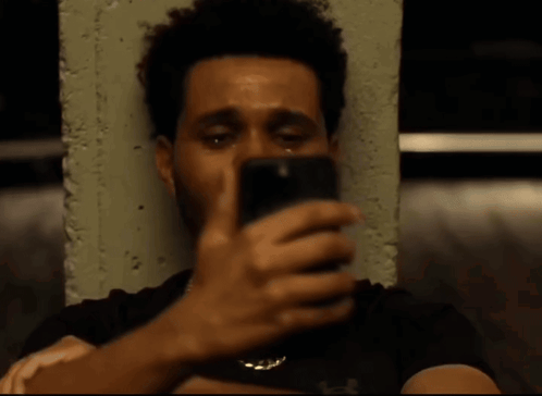 A Man With A Beard Is Crying While Sitting Next To A Concrete Wall . GIF