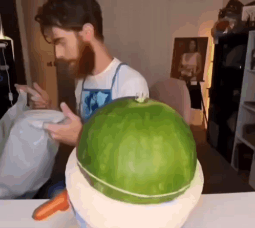 A Man With A Beard Is Cutting A Watermelon In Half GIF