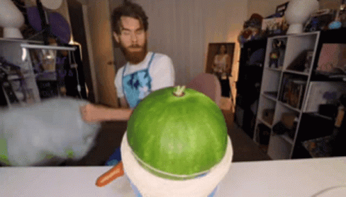 A Man With A Beard Is Cutting A Watermelon Into A Bowl . GIF