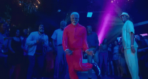 a man with a beard is dancing in a club with a group of people .