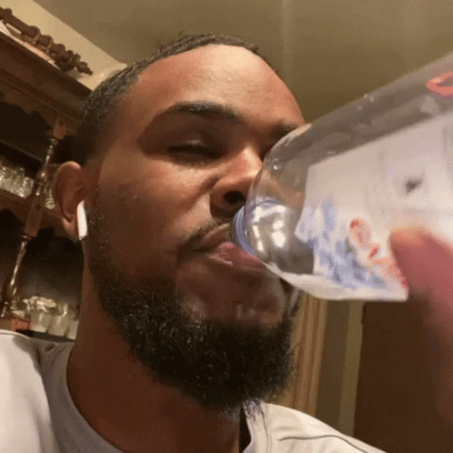 A Man With A Beard Is Drinking From A Bottle That Has The Word Bud Light On It GIF