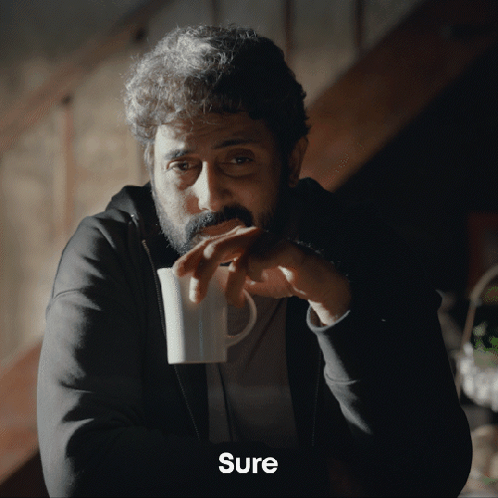 A Man With A Beard Is Drinking From A White Mug And The Word Sure Is On The Bottom GIF