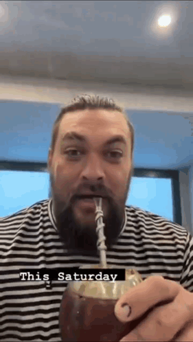 A Man With A Beard Is Drinking Through A Straw From A Coconut . GIF