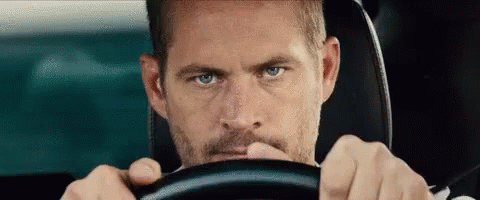 A Man With A Beard Is Driving A Car . GIF