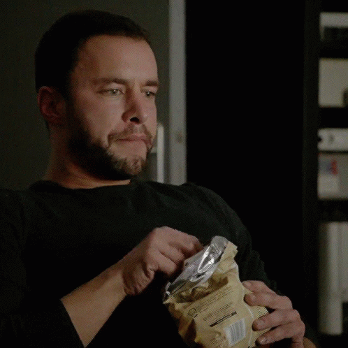 A Man With A Beard Is Eating A Bag Of Chips With A Fork GIF