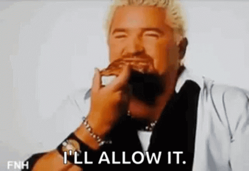 A Man With A Beard Is Eating A Hamburger With His Eyes Closed And The Words `` I 'Ll Allow It '' . GIF