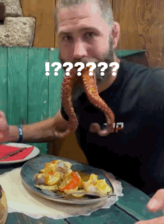 A Man With A Beard Is Eating A Plate Of Food With An Octopus Coming Out Of His Mouth .. GIF