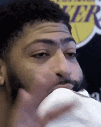 A Man With A Beard Is Eating Something In Front Of A Lakers Sign GIF