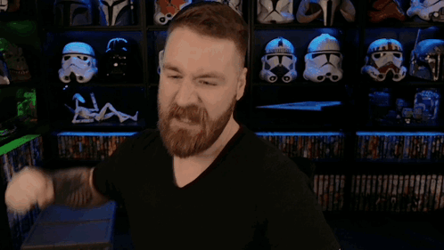A Man With A Beard Is Flexing His Muscles In Front Of A Shelf Full Of Storm Trooper Helmets GIF