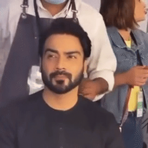 A Man With A Beard Is Getting His Hair Cut By A Hairdresser While A Woman Looks On . GIF