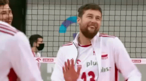 A Man With A Beard Is Giving A High Five To Another Man While Wearing A Volleyball Uniform . GIF