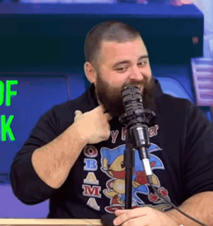 A Man With A Beard Is Giving A Thumbs Up While Talking Into A Microphone . GIF