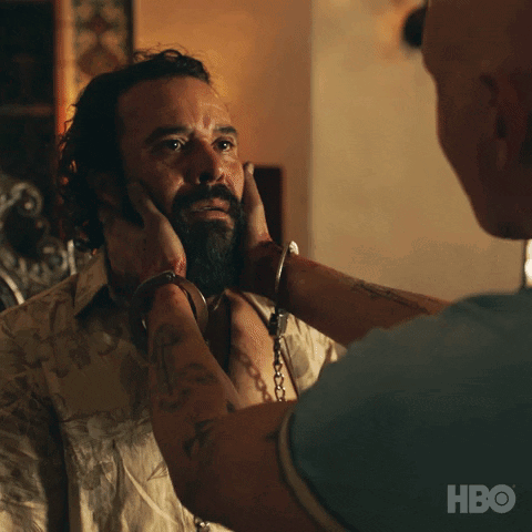 a man with a beard is handcuffed to another man 's neck and hbo is visible on the bottom right