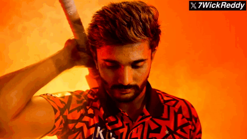 A Man With A Beard Is Holding A Bat In Front Of A Sign That Says 7Wick Reddy GIF