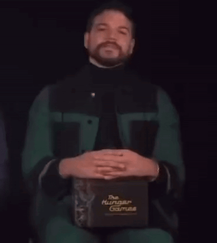 A Man With A Beard Is Holding A Box That Says The Hunger Games GIF