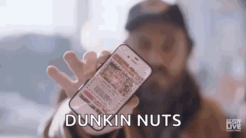a man with a beard is holding a cell phone in his hand .