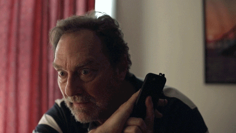 a man with a beard is holding a cell phone in his hand