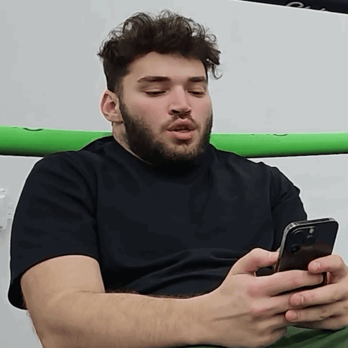 A Man With A Beard Is Holding A Cell Phone GIF
