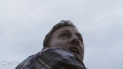 A Man With A Beard Is Holding A Chainsaw In His Hands . GIF