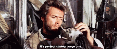 a man with a beard is holding a doll and says it 's perfect timing large one .
